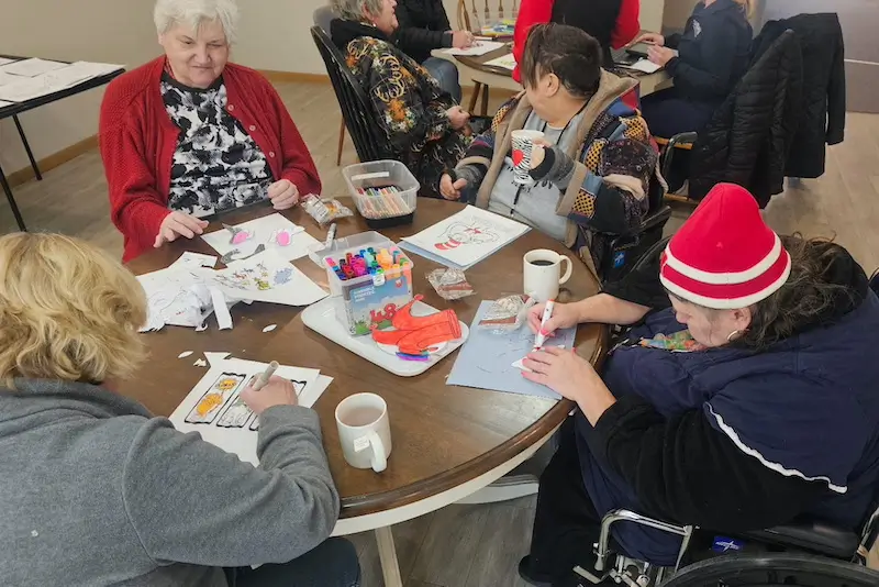 Residents doing crafts together around a table at French Meadow Place