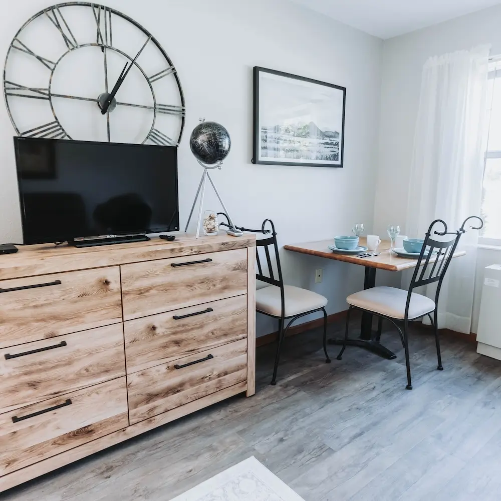 Apartment with a dresser, wall clock and small dining table by the window