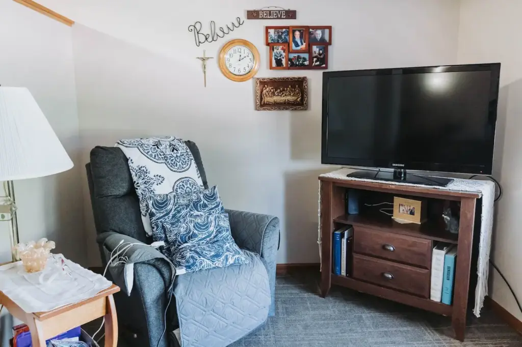 Resident apartment living area with a recliner and television at French Meadow Place