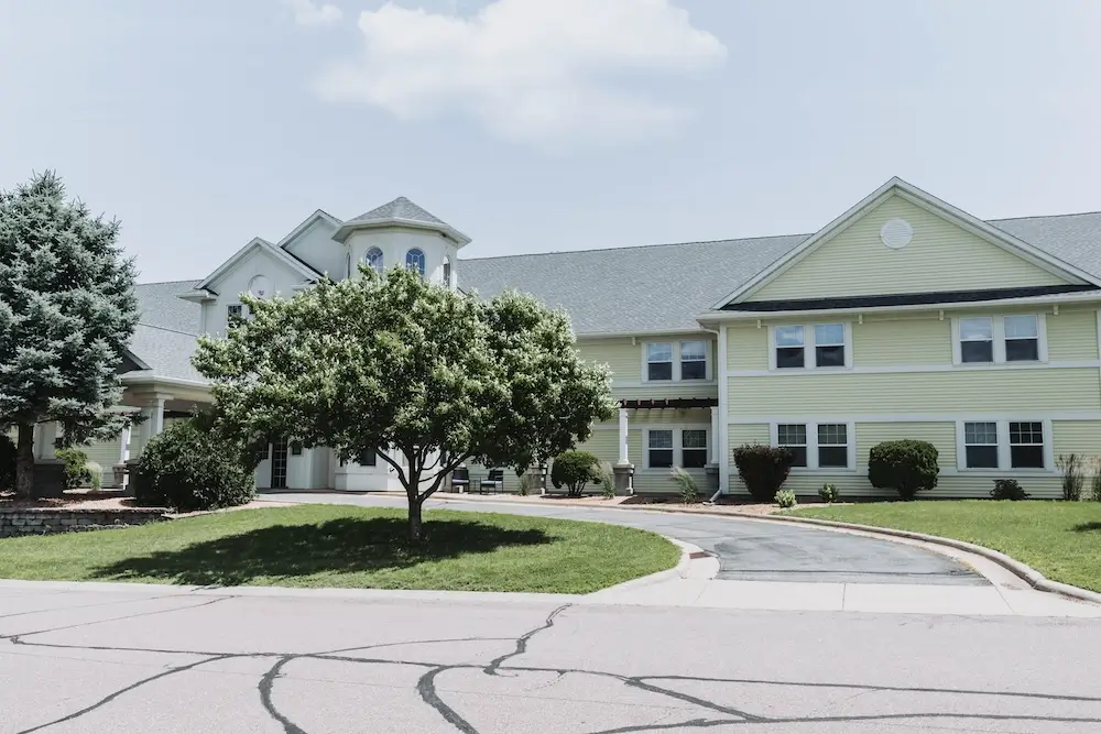Front of French Meadow Place with a shade tree and circular drive