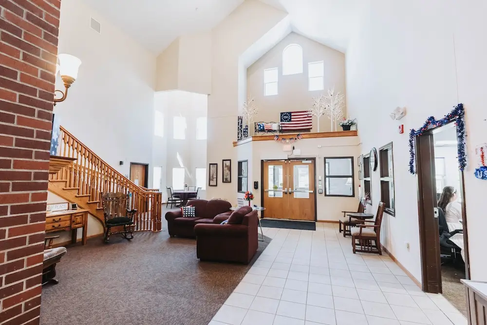 Two-story lobby at French Meadow Place with sofas and a wooden staircase